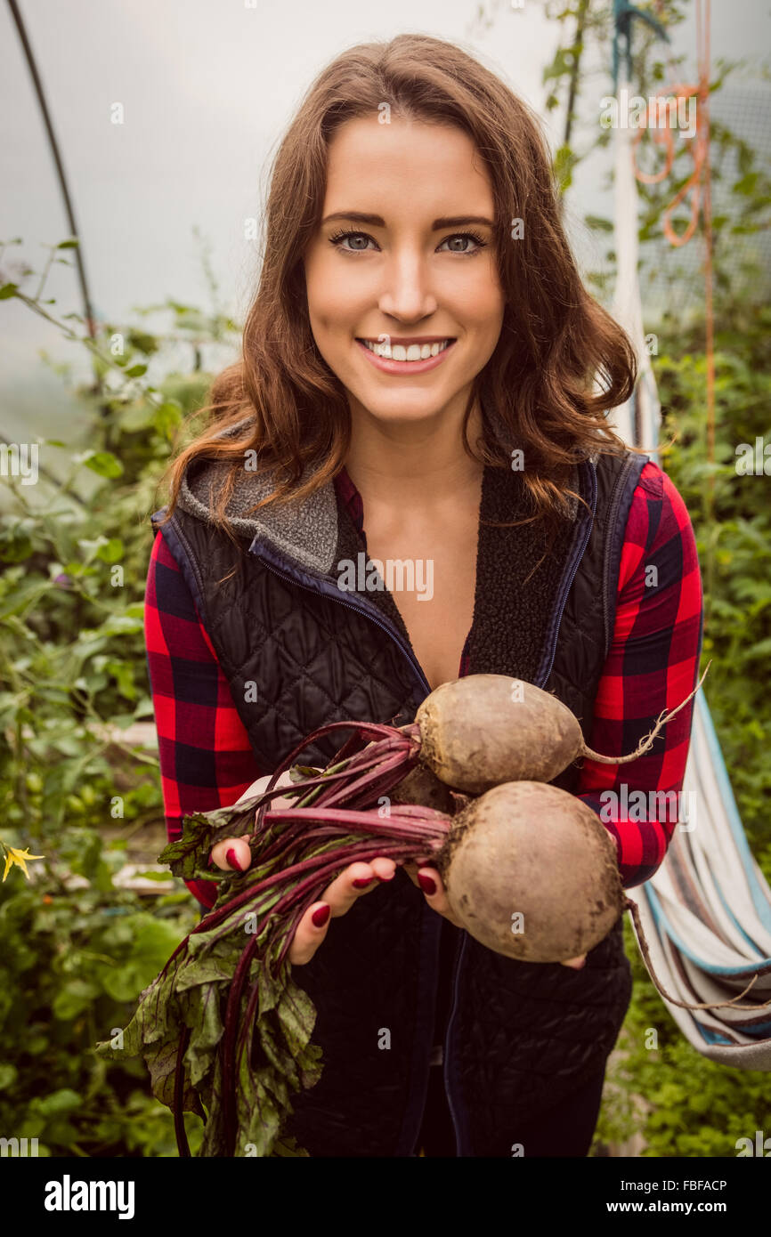 Lächelnde Frau hält und zeigt rote Beete Stockfoto