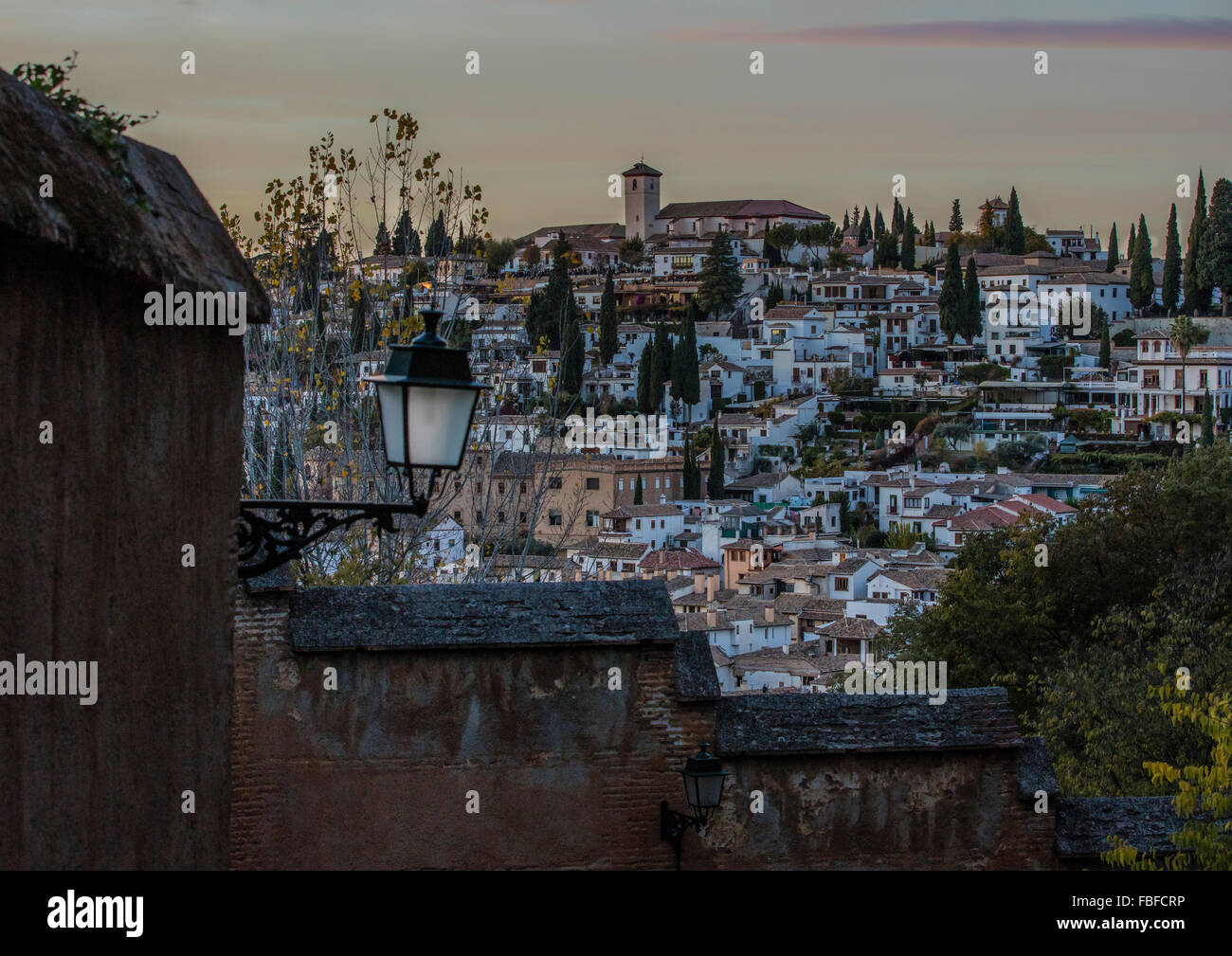 Der Albaicín in Granada in der Abenddämmerung am Fuße der Alhambra. Man kann Menschen in das Mirador San Nicolas an der Wand sehen. Stockfoto