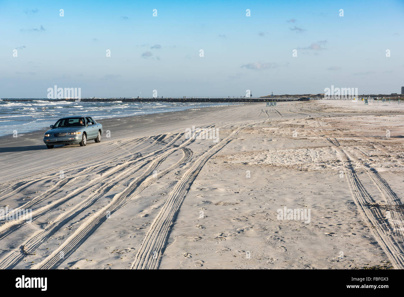 Blau Limousine in Richtung Kamera fahren am Strand in der Nähe der atlantischen Ozean in Ponce Inlet Lighthouse Park mit Reifenspuren und Verkehrszeichen in der Nähe von Daytona Beach. Stockfoto