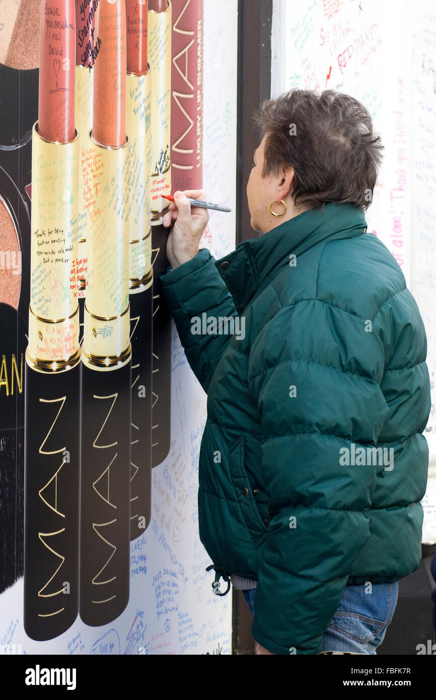 Frau, die eine Hommage an die späten David Bowie an das mittlerweile berühmte Wandgemälde des späten David Bowie in Brixton schreiben Stockfoto