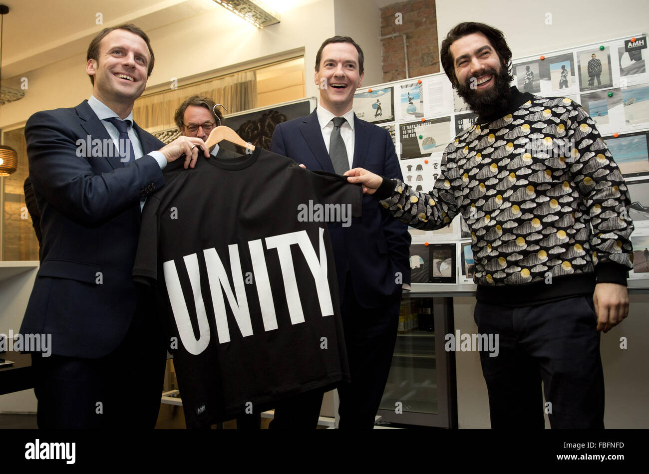 Berlin, Deutschland. 14. Januar 2016. Französische Wirtschaftsministerin Emmanuel Macron (l-R) und britische Schatzkanzler George Osborne erhalten ein T-shirt mit dem Wort "Einheit" von Ashley Marc Hovelle bei einem Besuch in der Fabrik in Berlin, Deutschland, 14. Januar 2016. Foto: Jörg CARSTENSEN/DPA/Alamy Live-Nachrichten Stockfoto