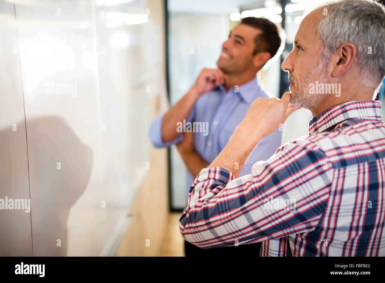 Lächelnde Geschäftsleute mit Hand am Kinn Stockfoto