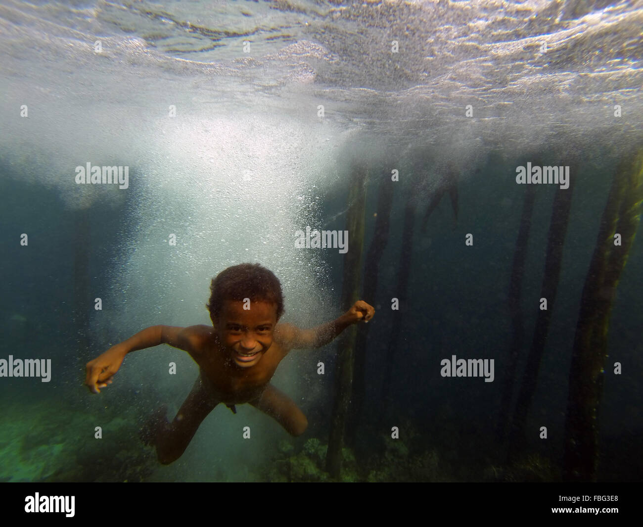 Jungen unter Wasser nach dem Sprung aus Steg, Gam Insel, Raja Ampat, West Papua, Indonesien Stockfoto