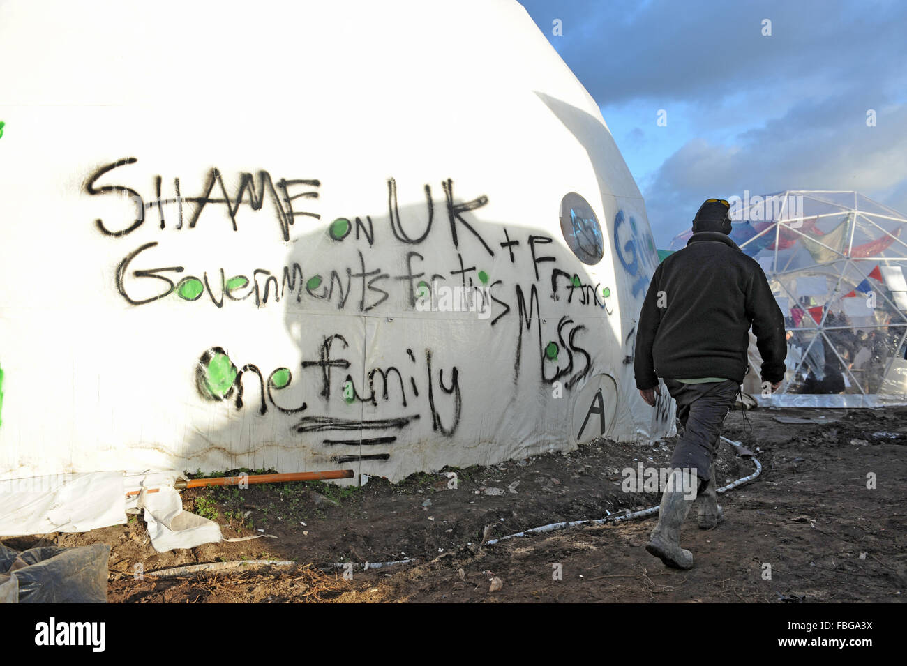 Dschungel, Calais, Frankreich. Ein Mann geht vorbei ein handgemaltes Schild in der Kuppel, des guten Chance Theaters, die besagt "Schande über Großbritannien und Frankreich Regierungen für diesen Schlamassel. Eine Familie. " Stockfoto