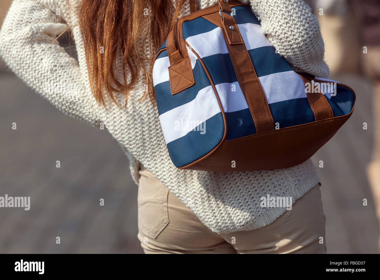 Junge Frau in weißem Pullover mit Handtasche über Schulter, Street Lifestyle Mode Stockfoto