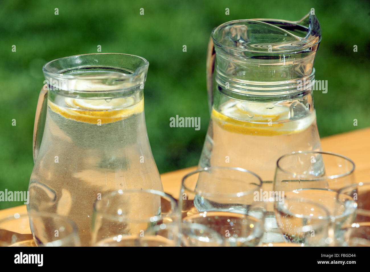 Die zwei Karafes mit frischem Wasser mit Zitronengeschmack und Gläser auf einem Tisch im Garten Stockfoto