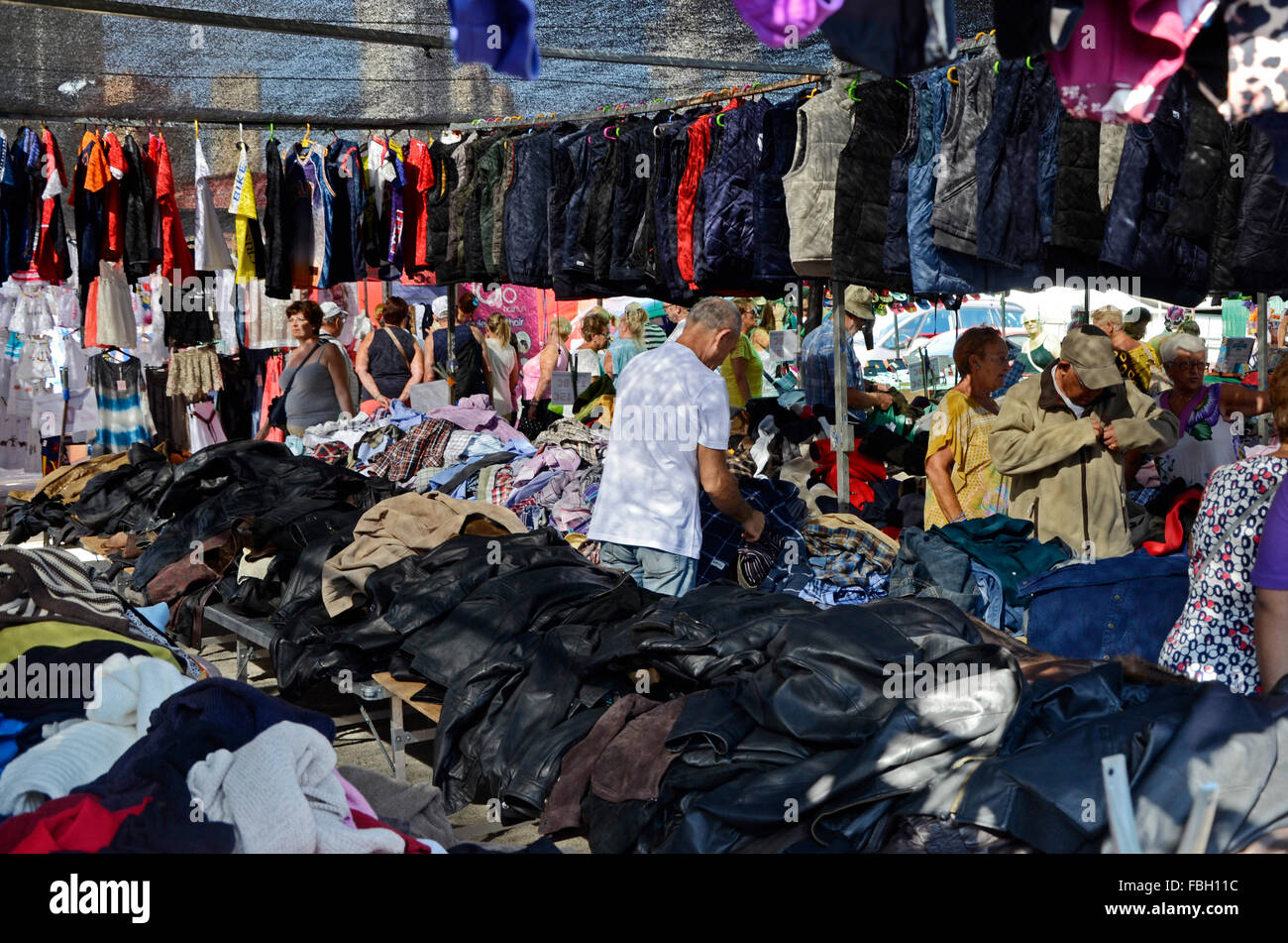 Männer und Frauen Graben durch das Angebot eines Standes Verkauf verwendet Kleidung auf einem Markt in Benidorm, Alicante, Spanien Stockfoto