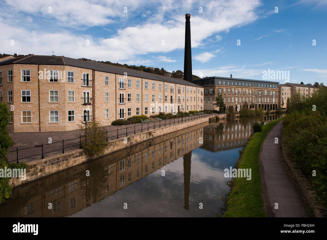 Britannia Wharf, Leeds-Liverpool-Kanal, Bingley, GB - Mühle mit Schornstein, umgewandelt in Wohnungen, spiegelt sich im Wasser. Stockfoto