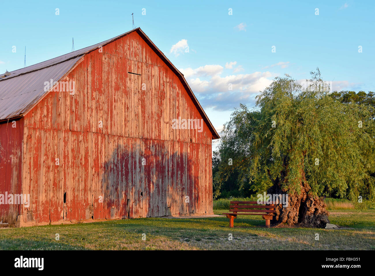 Verwitterte Holz rote Scheune mit Baum Schatten in Michigan. Stockfoto