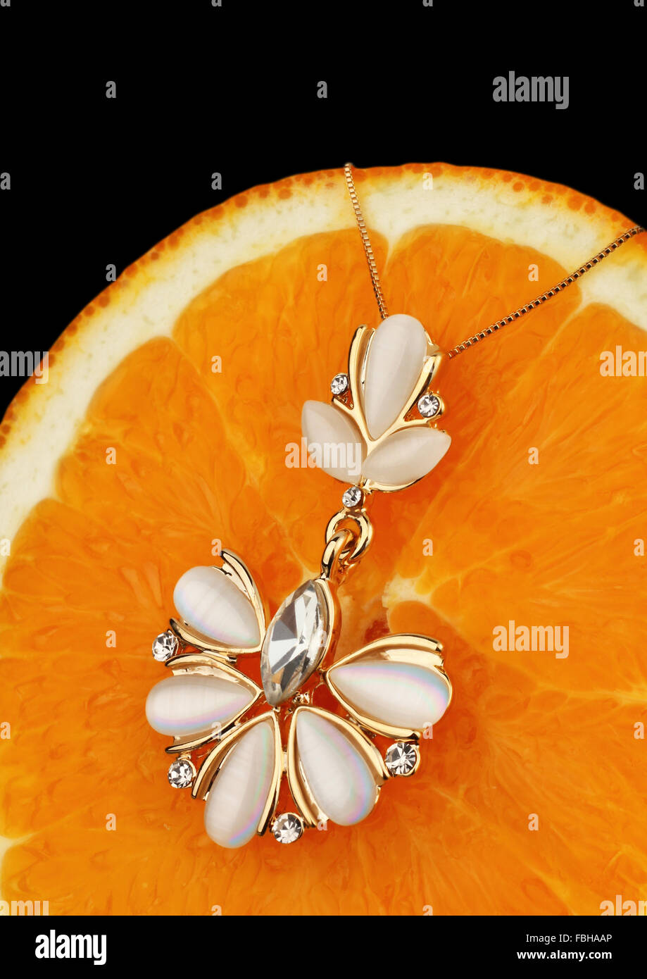Goldschmuck mit Perlmutt und Diamanten auf orangem Hintergrund Stockfoto
