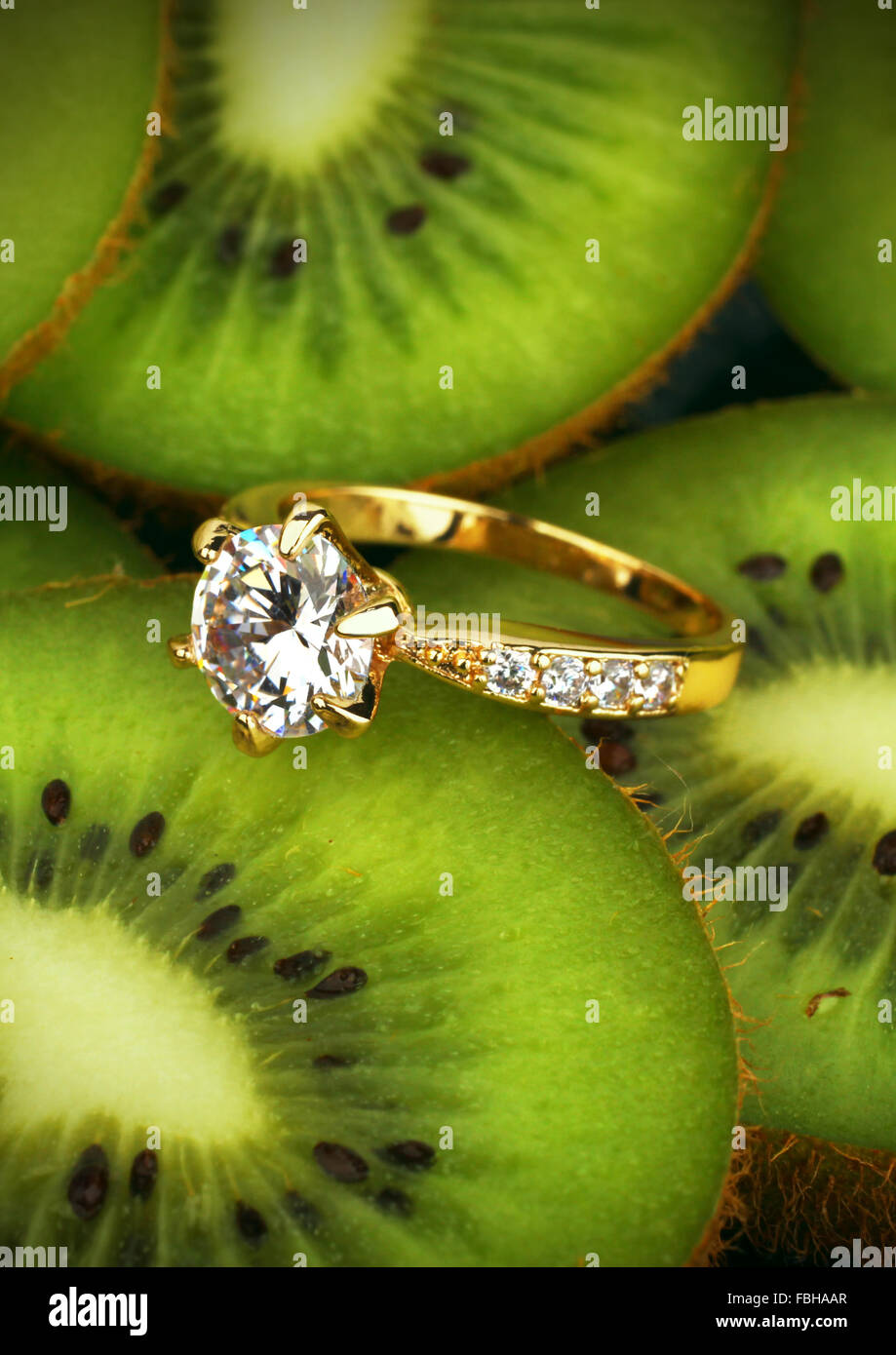 Schmuck Ring mit großen Diamanten auf Kiwi Frucht Hintergrund, vertikale Zusammensetzung Stockfoto