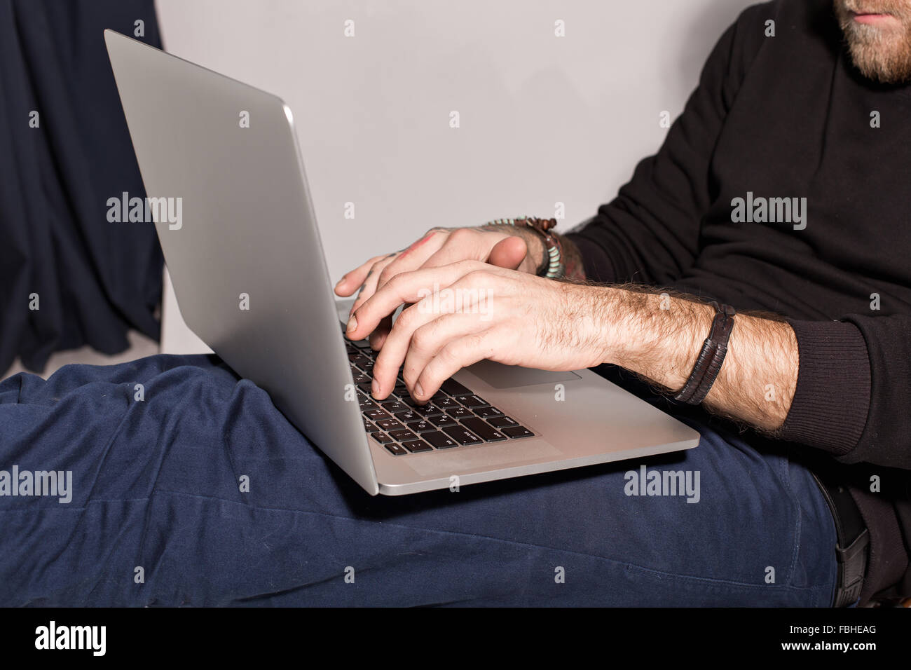 junger Mann mit einem Bart mit einem Laptop sitzen und mit Blick auf den monitor Stockfoto