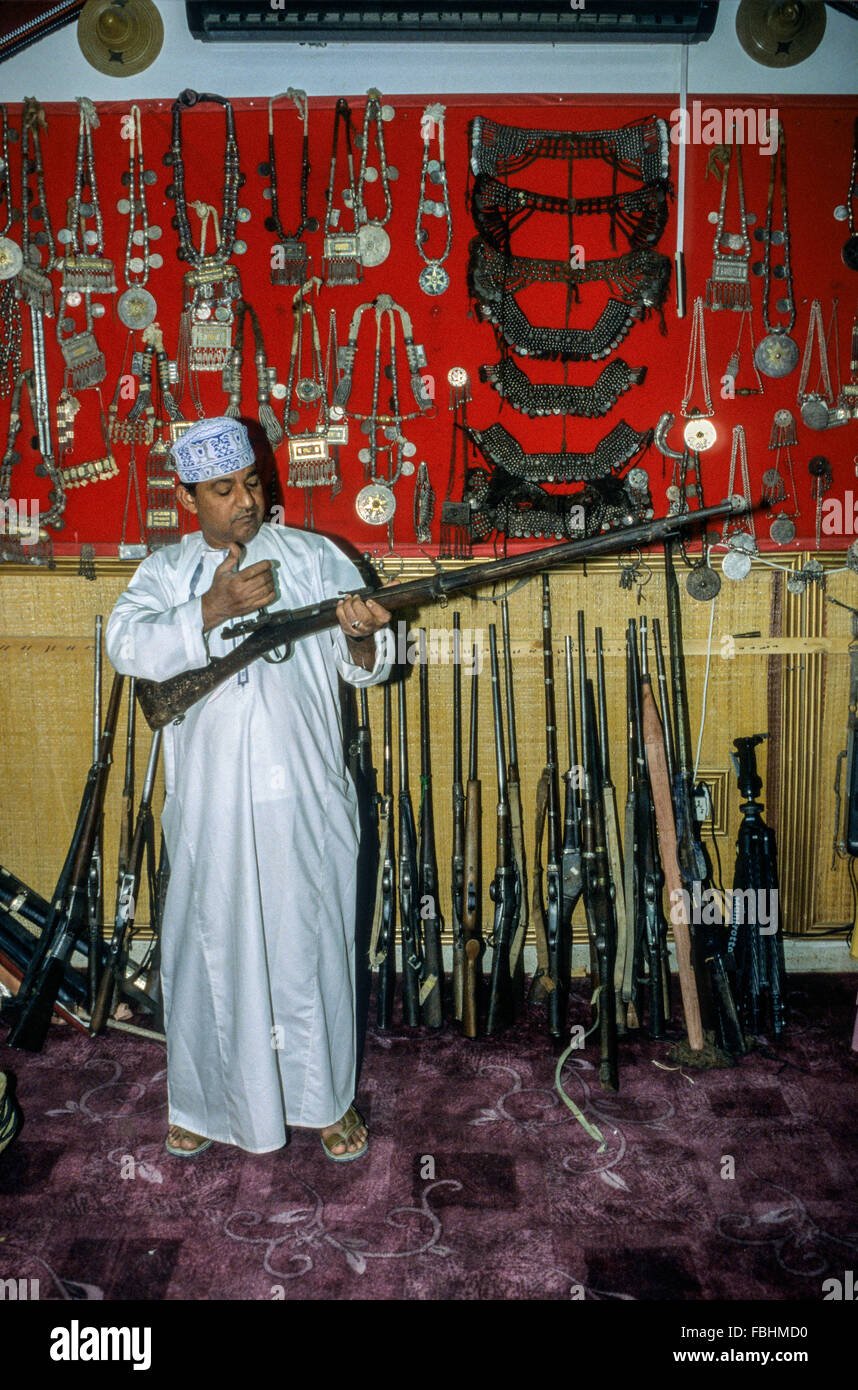 Nizwa, Oman.  Souvenir-Shop.  Shopper, eine alte Pistole zu prüfen. Stockfoto