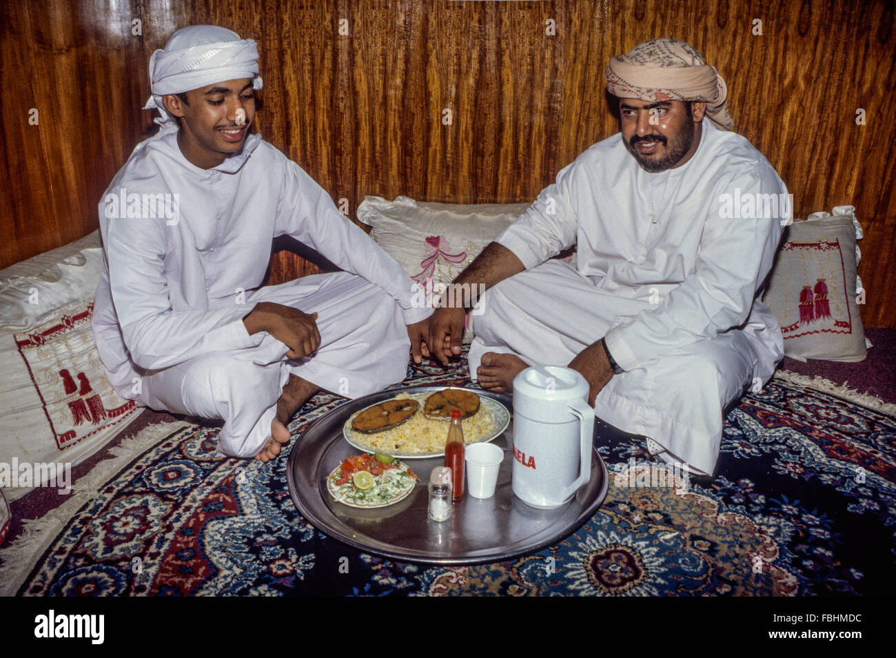Nizwa, Oman.  Sitzen auf dem Boden in einem omanischen Restaurant für das Mittagessen von Fisch, Reis und Salat. Stockfoto