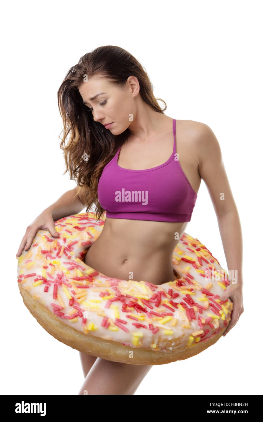 Fitness-Frau mit einem großen Donut um ihre Taille zu symbolisieren, Gewichtszunahme Stockfoto
