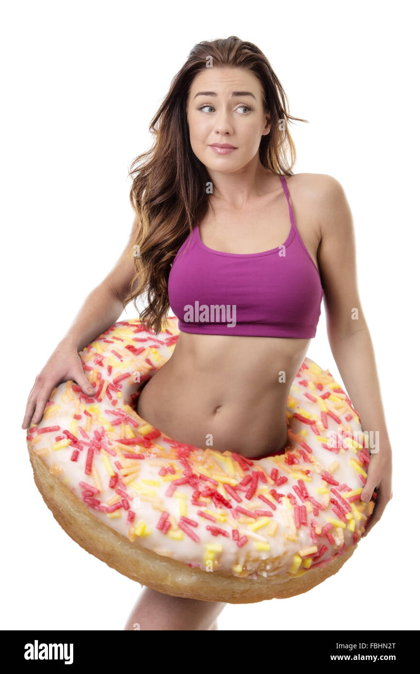 Fitness-Frau mit einem großen Donut um ihre Taille zu symbolisieren, Gewichtszunahme Stockfoto