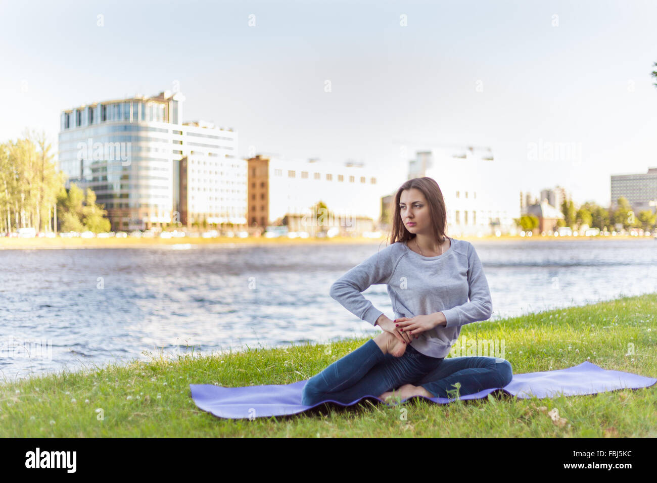 Schöne sportliche ruhige junge Frau arbeiten auf sonnigen Straße, Aufwärmen, stretching-Übungen am Ufer des Flusses im Park, si Stockfoto