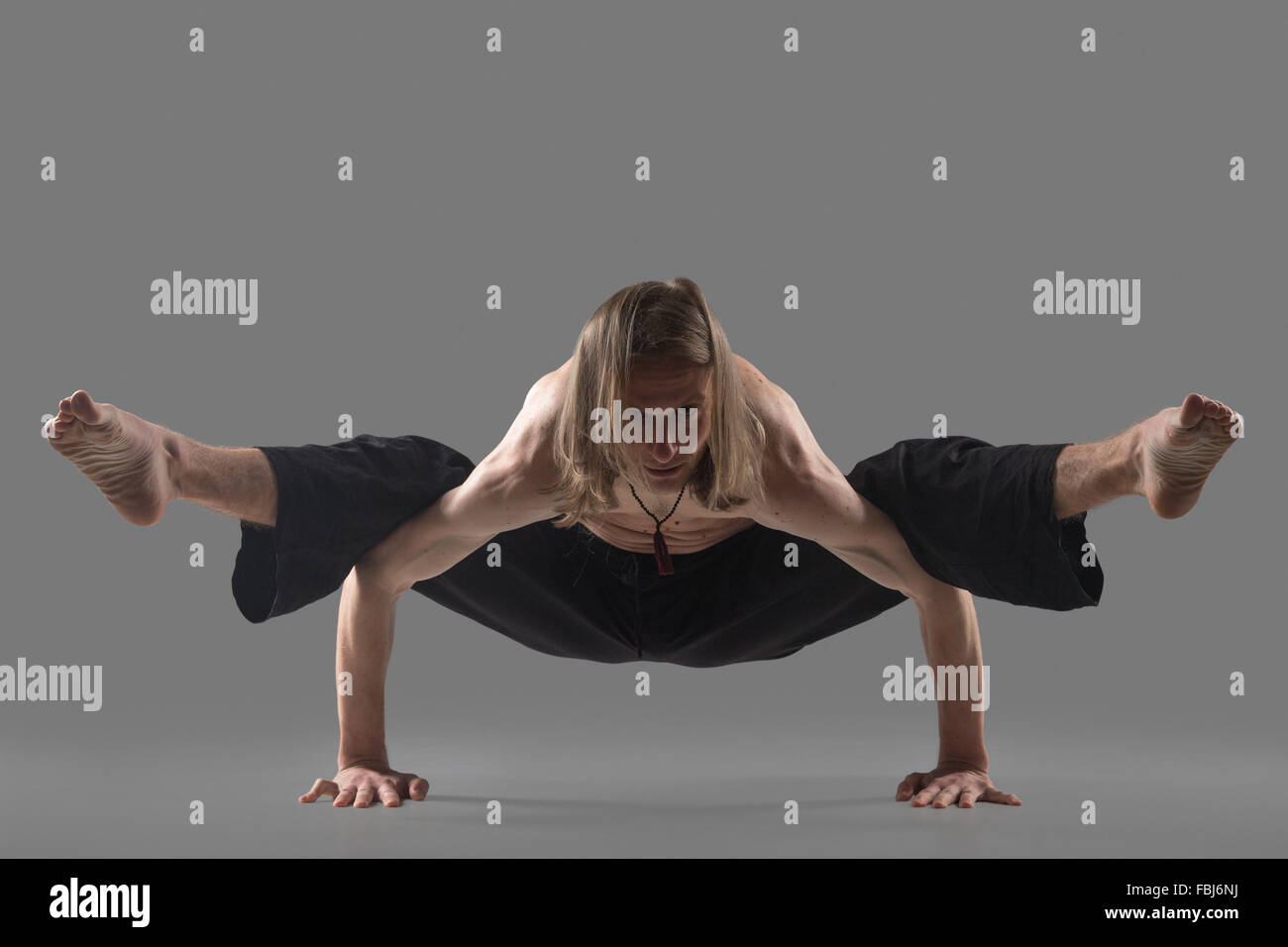 Sportliche junge Mann in schwarz Hose tun Yoga-Pose, stehend im Arm Gleichgewicht, Variation von Firefly Körperhaltung, Asana TIFF zu stärken Stockfoto