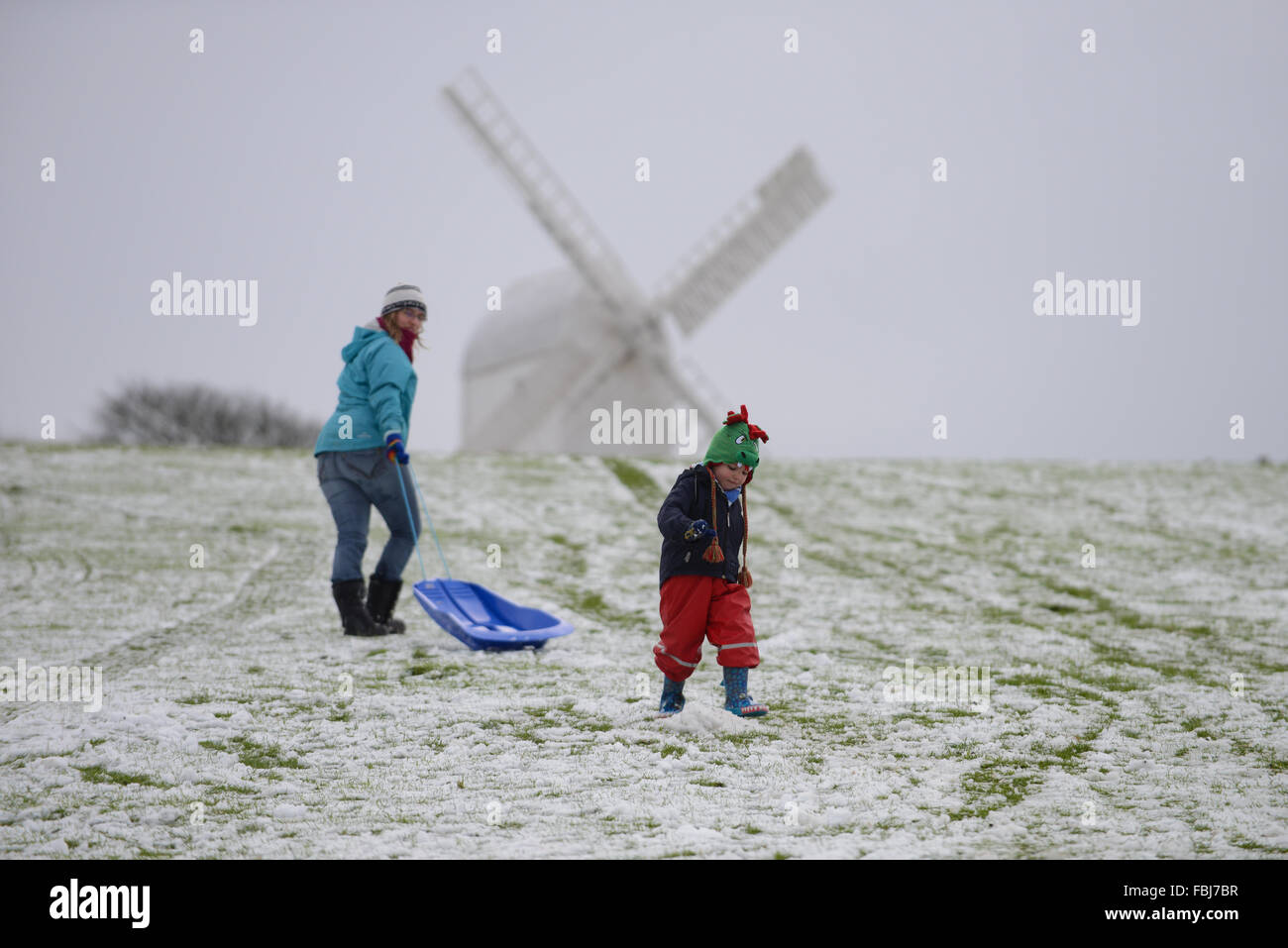 Eine Mutter und ihr Sohn haben Spaß im Schnee vor Clayton Windmühlen an einem Wintertag in Clayton, East Sussex, UK. Stockfoto