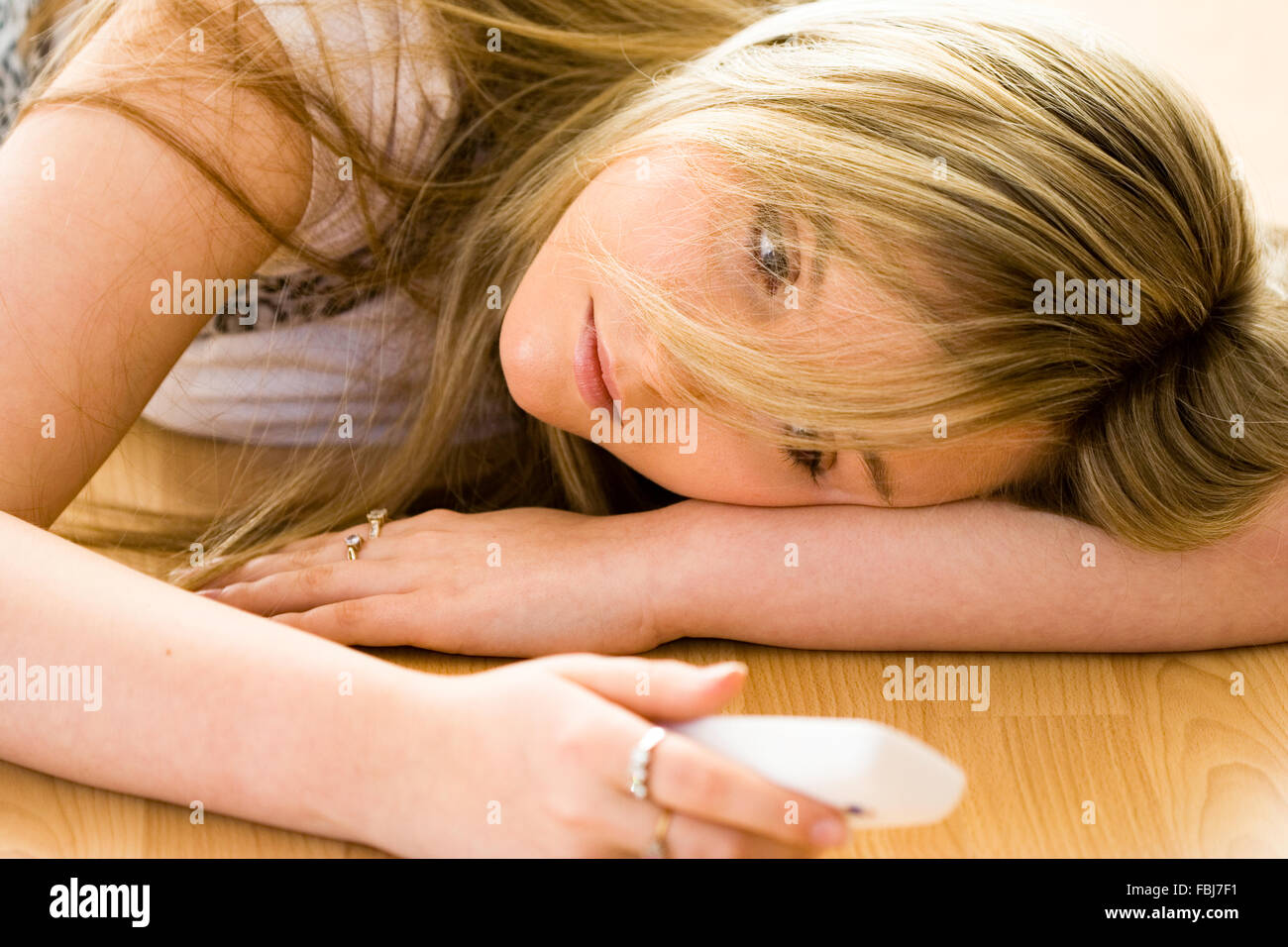 Schöne junge Frau, 16 Jahre alt, Kopf und Schultern, blond, blaue Augen, mit traurigen Ausdruck, Telefon, während am Boden. Soft Focus Stockfoto