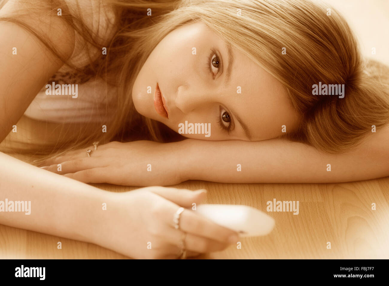 Schöne junge Frau, 16 Jahre alt, Kopf und Schulter, blond, blaue Augen, mit traurigen Ausdruck, Telefon, während am Boden. Auge - Kontakt. Stockfoto