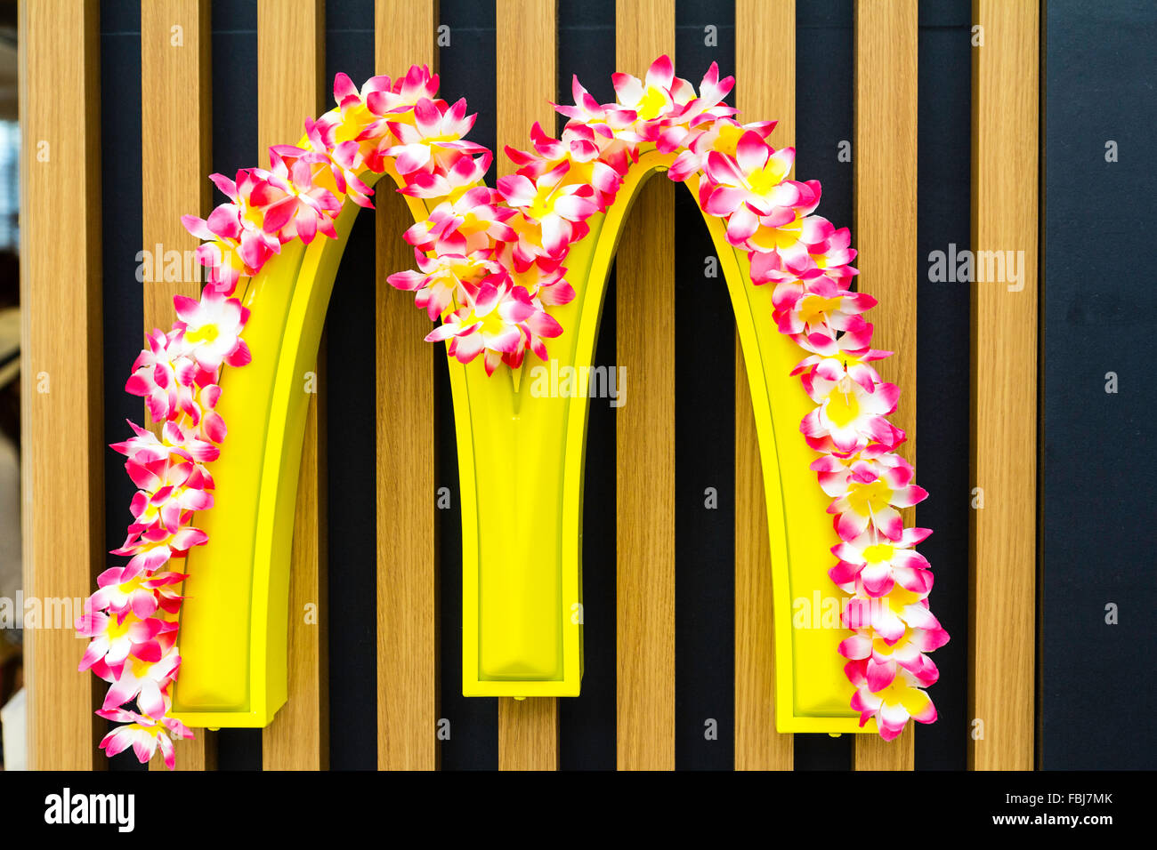 Japan. McDoanld des 'gelben Logo auf Holzstäbchen Hintergrund mit Blüten drapiert über der Oberseite. Stockfoto