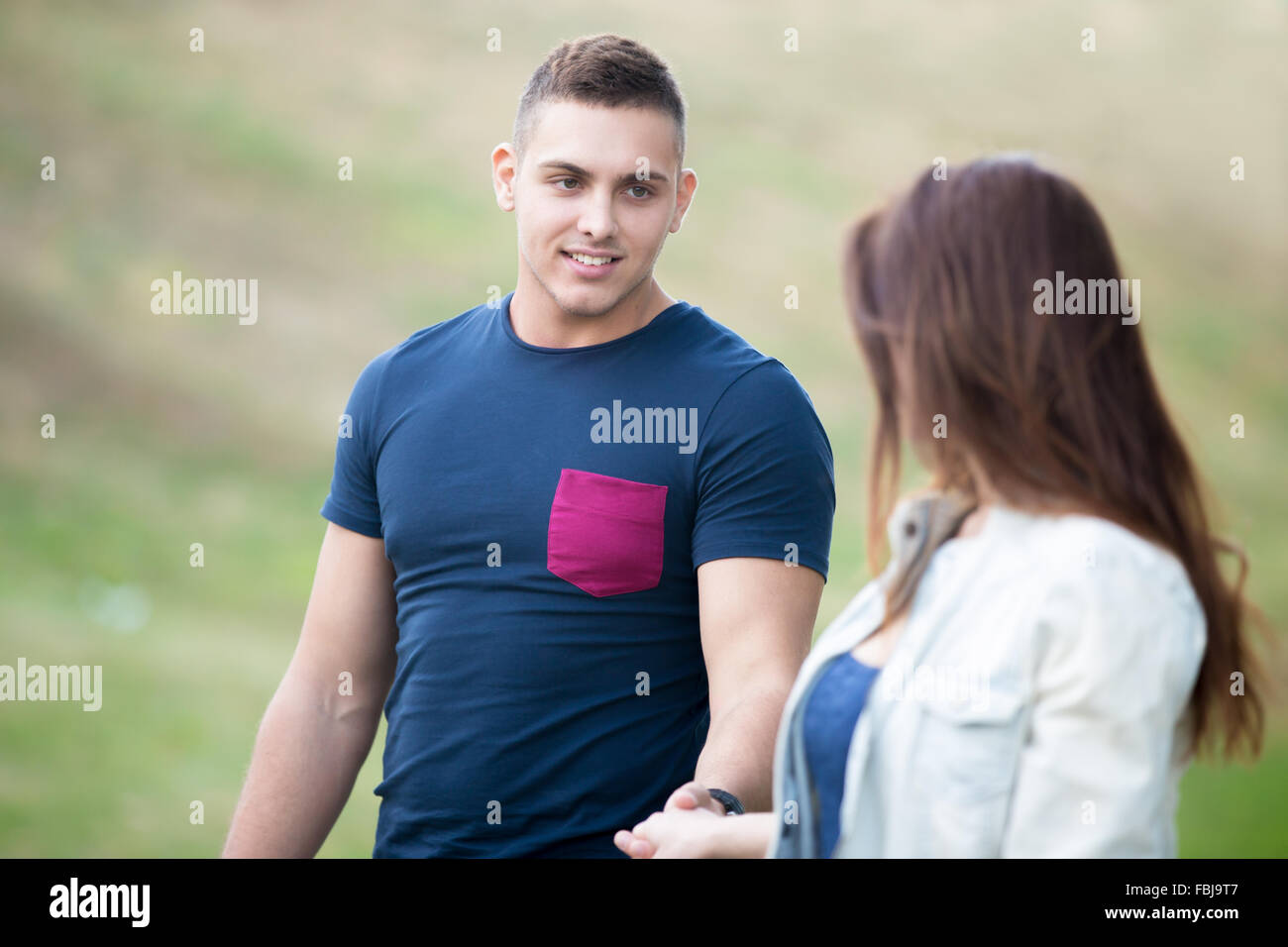 Hübscher Kerl seine Freundin Hand hält, folgt ihr, schöne junge Paar in der Liebe, zu Fuß im Park an einem Tag tragen Casu Stockfoto