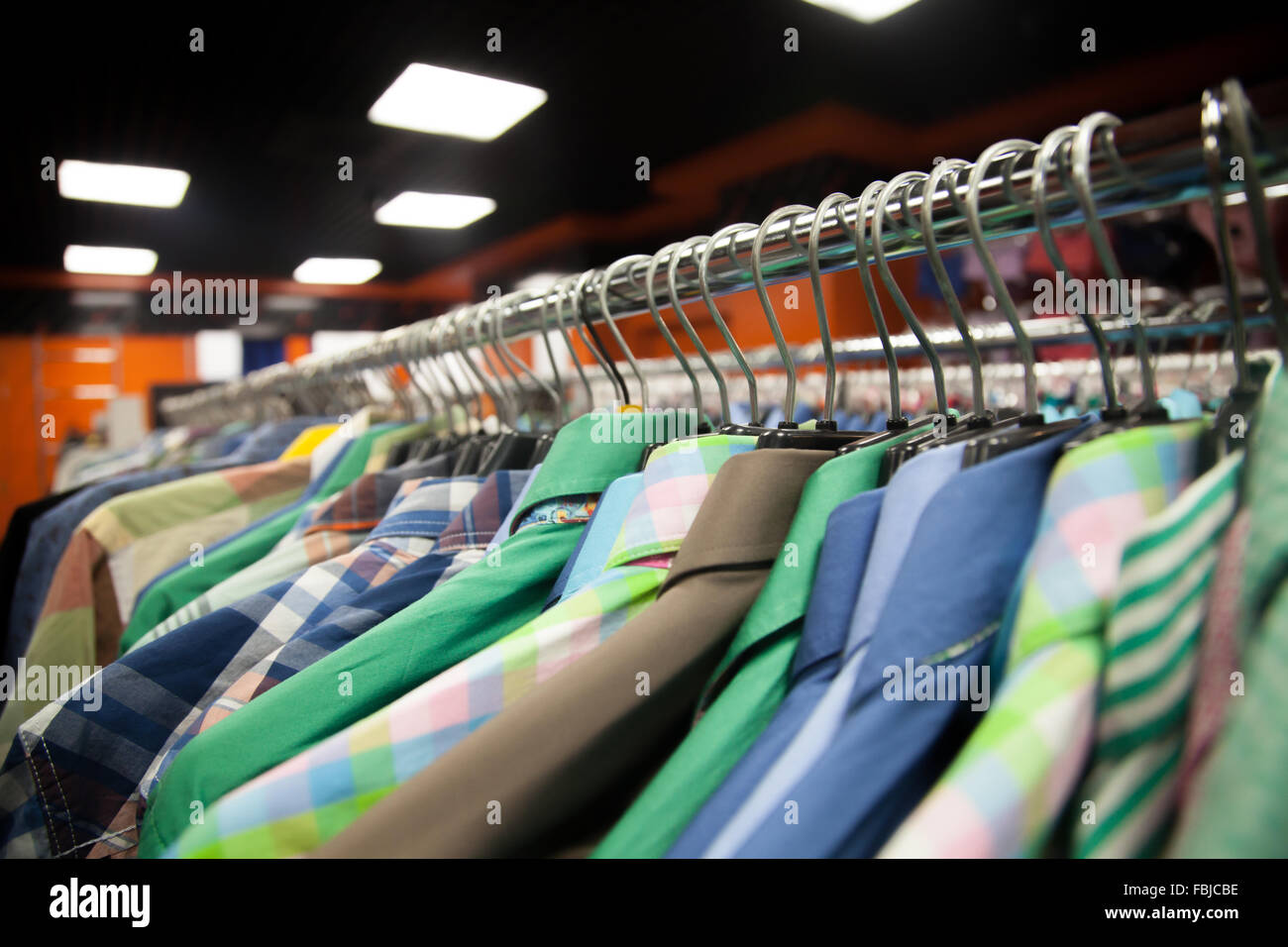 Kleiderbügel mit bunten männlichen Shirts in der Fashion Mall, Nahaufnahme Stockfoto