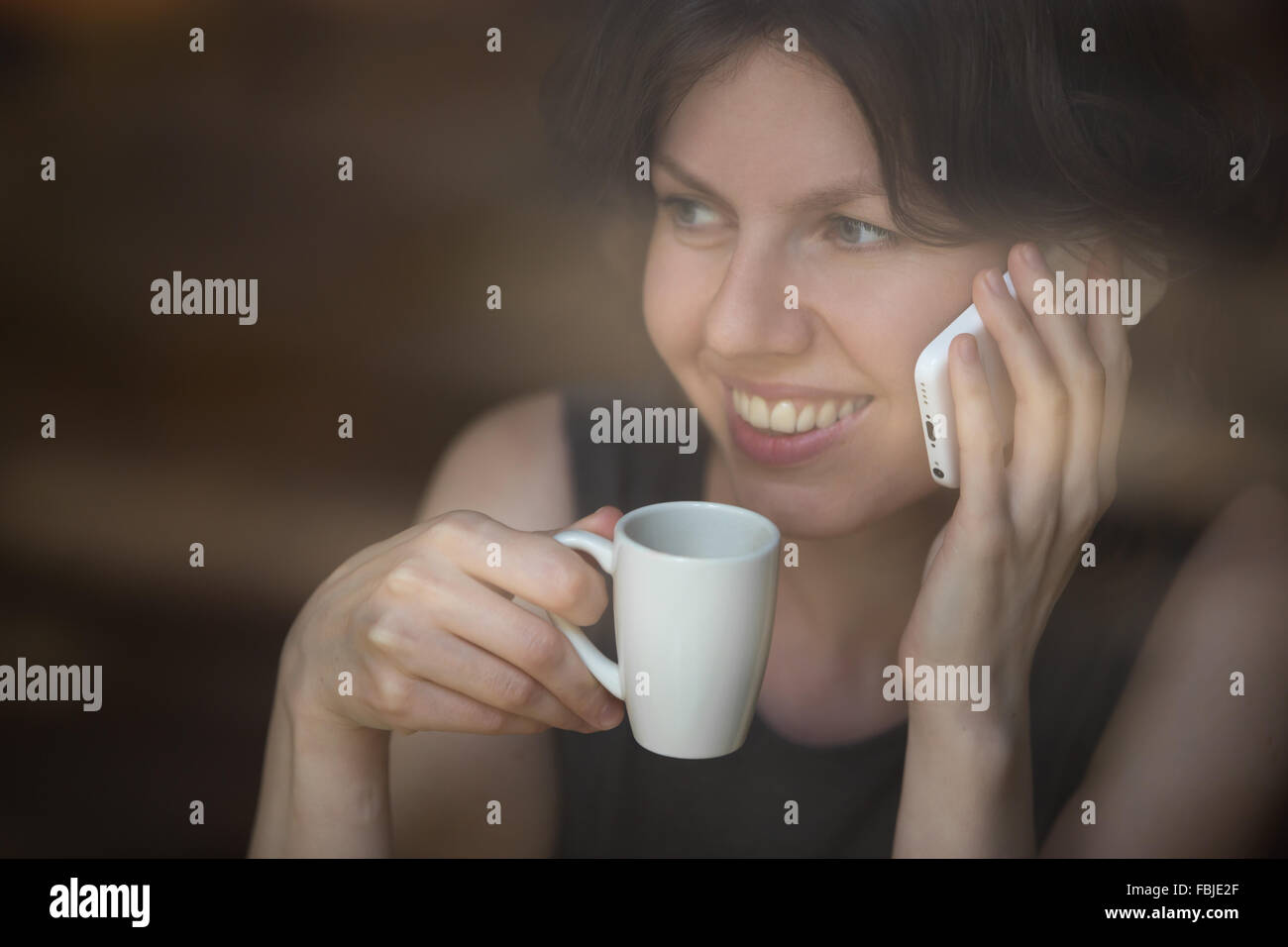 Porträt von glücklich Frau mit Handy und eine Tasse Kaffee im modernen Café mit Smartphone, telefonieren, telefonieren Stockfoto