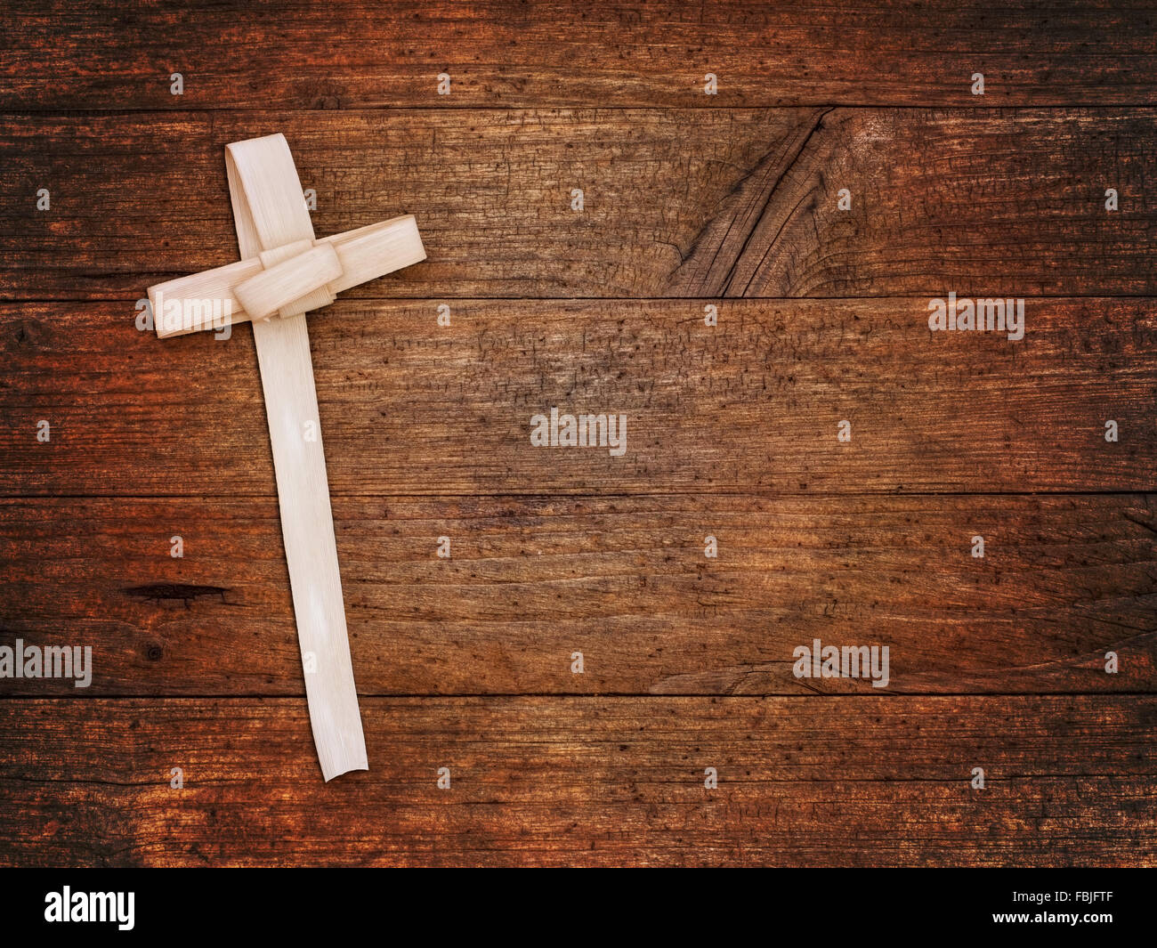 Palmsonntag-Hintergrund - Kreuz aus Palmblatt auf dunklem Holz gefertigt. Stockfoto