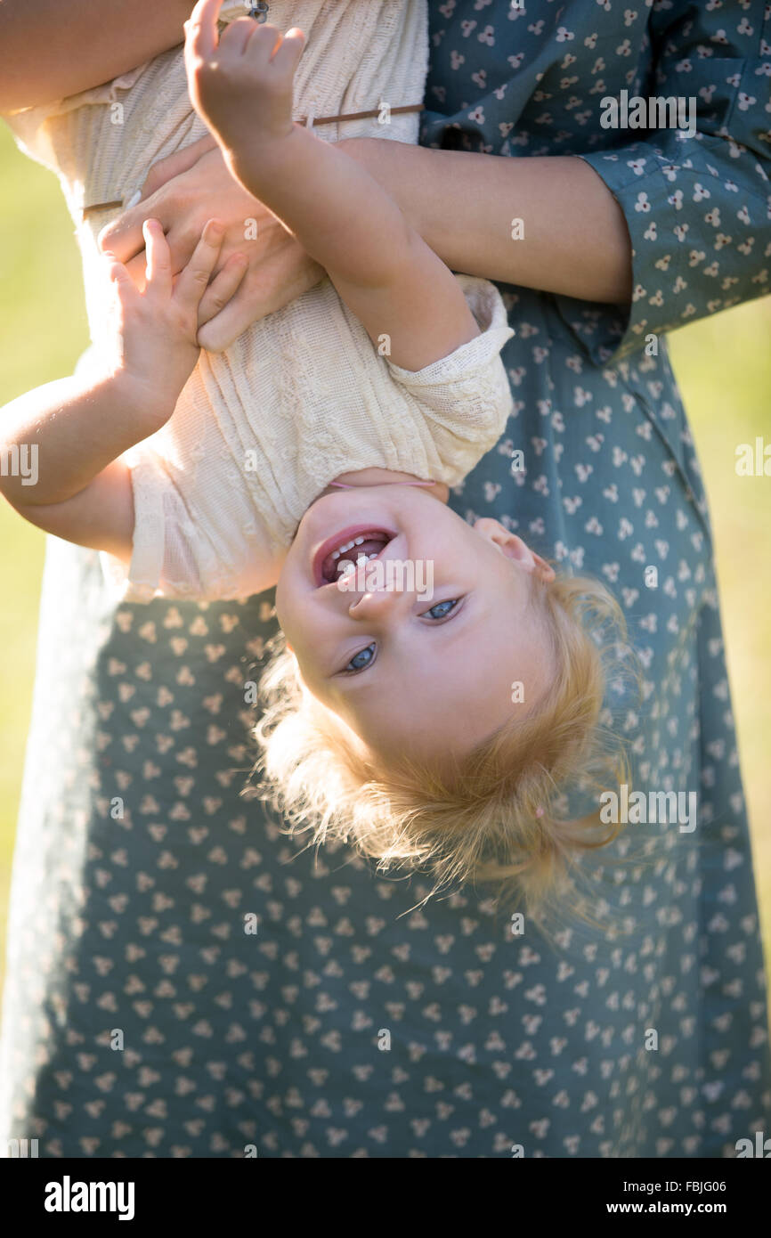 Junge Mutter und fröhlich liebenswert blond Tot Mädchen spielen, gemeinsam Spaß haben im Park im Sommer Mutter hielt sie spielerisch Stockfoto