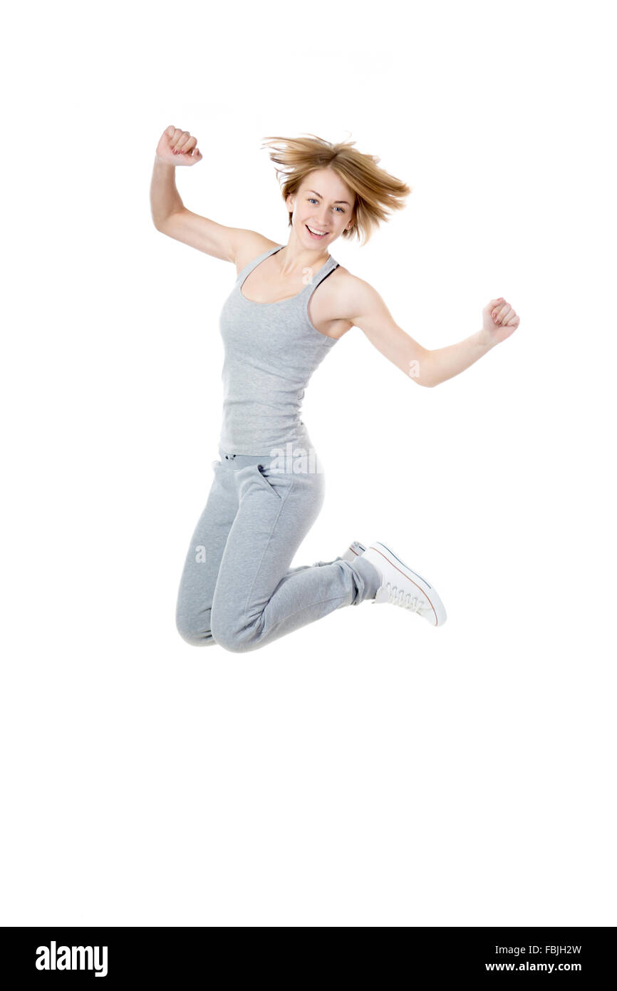 Porträt des jungen glücklich lächelnde schlank sportlich schöne Frau tragen graue Sportbekleidung, springen vor Freude, isoliert Studio Bild auf Stockfoto