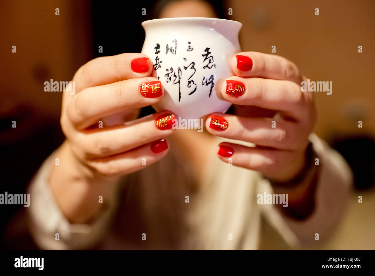 Maniküre mit Hieroglyphen Nahaufnahme. Attribute, die das chinesische Neujahr Frühlingsfest. Asiatische Frau bietet Tasse Tee Zeremonie. Stockfoto