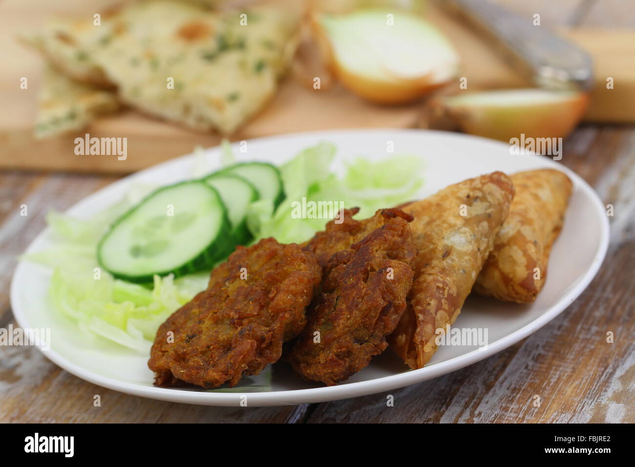 Indische Snacks wie Zwiebel-Bhajis und Samosas und grüner Salat Stockfoto