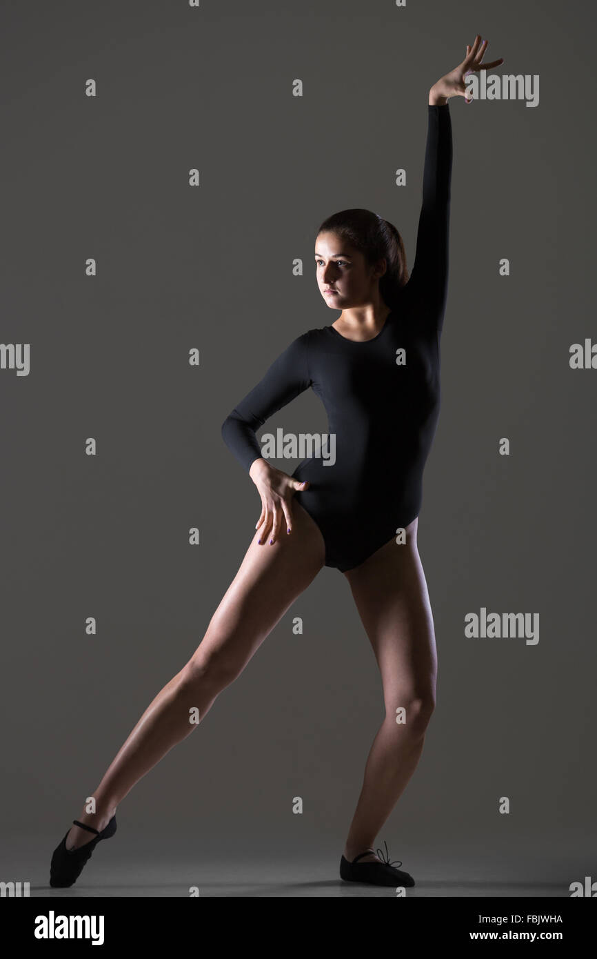 Porträt von schöne junge Tänzerin Frau in schwarzer Kleidung trainieren, tanzen, Ganzkörperansicht, Studio, dunkler Hintergrund Stockfoto