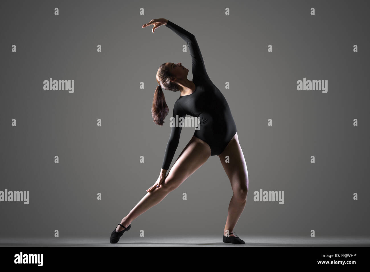 Porträt von schöne junge moderne Tänzerin Frau im schwarzen Trikot, Sport, tanzen, Ganzkörperansicht, Studio, dunkler Hintergrund Stockfoto