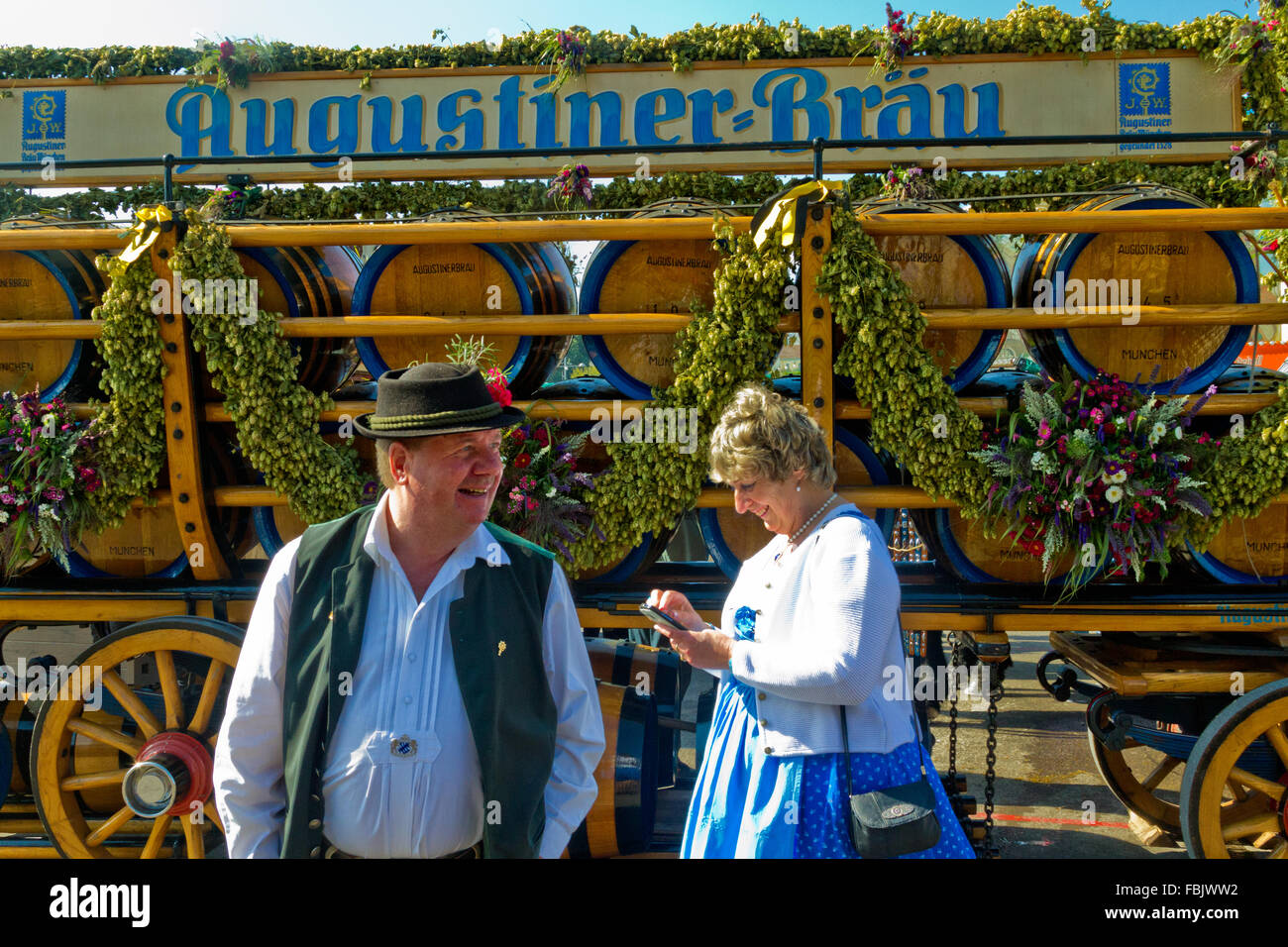 Paar steht vor Wagen beladen mit Bierfässern auf dem Oktoberfest in München. Stockfoto