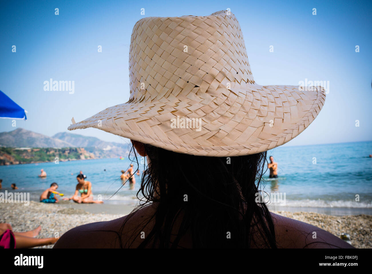 Ein Urlauber entspannt auf einem spanischen Strand tragen einen Strohhut. Stockfoto