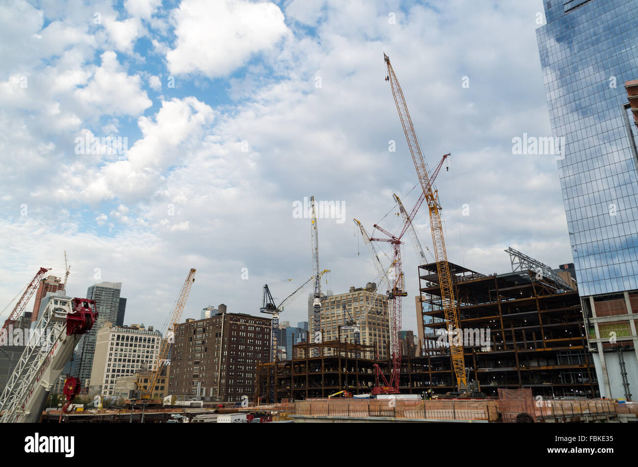 Werden mehrere Krane und schweres Heben-Maschinen auf einer Baustelle in Chelsea, New York City, als neue Wolkenkratzer gebaut. Stockfoto