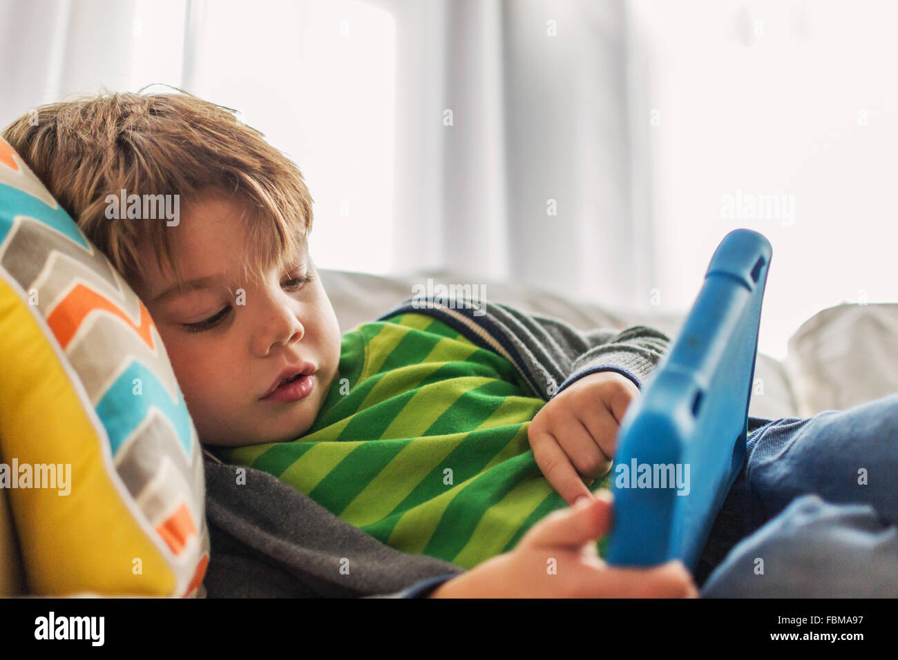 Junge auf Couch mit digital-Tablette zu spielen Stockfoto
