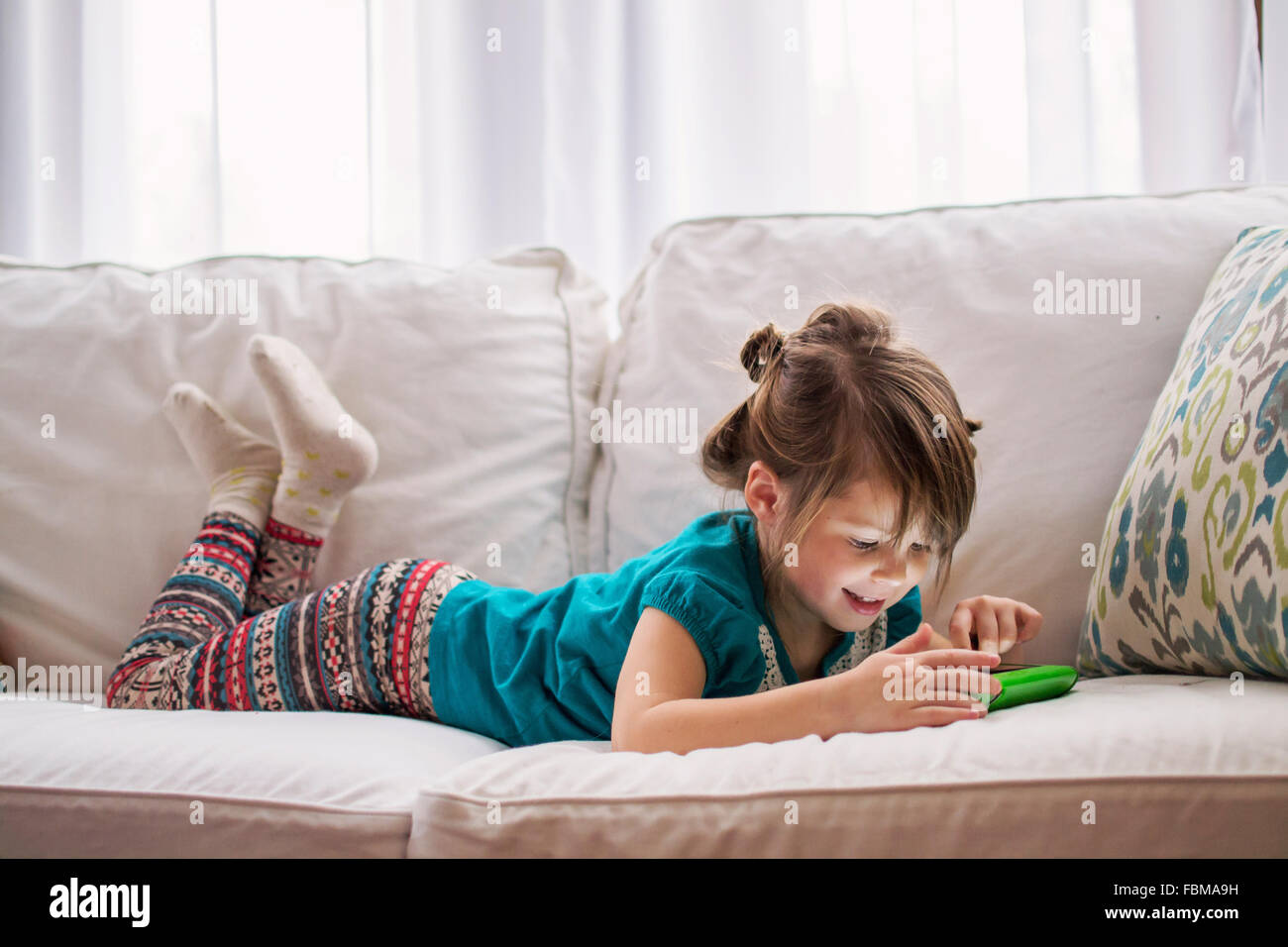 Mädchen auf Couch mit digital-Tablette zu spielen Stockfoto