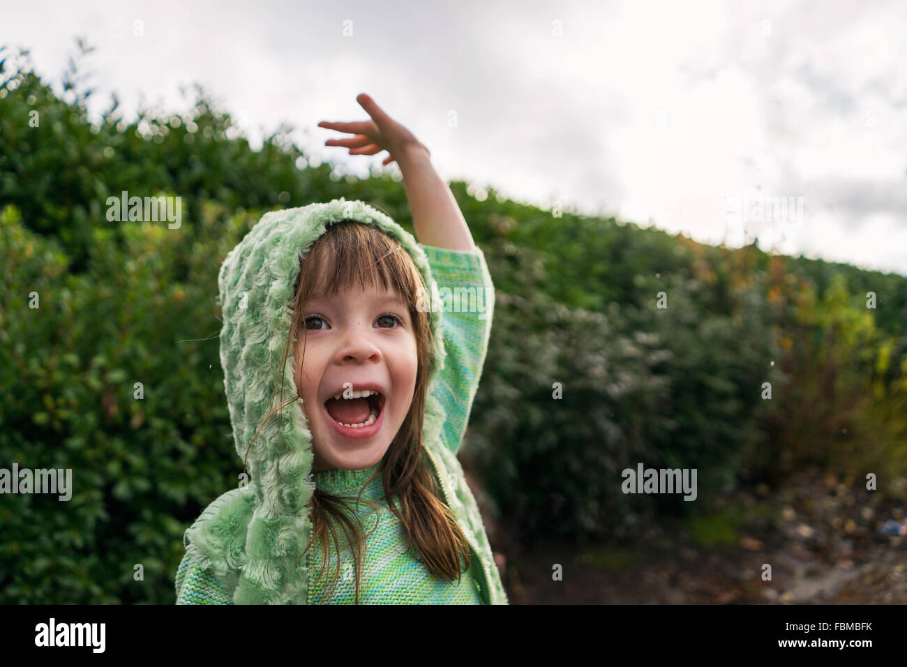 Aufgeregt Mädchen mit erhobenem Arm im Regen Stockfoto