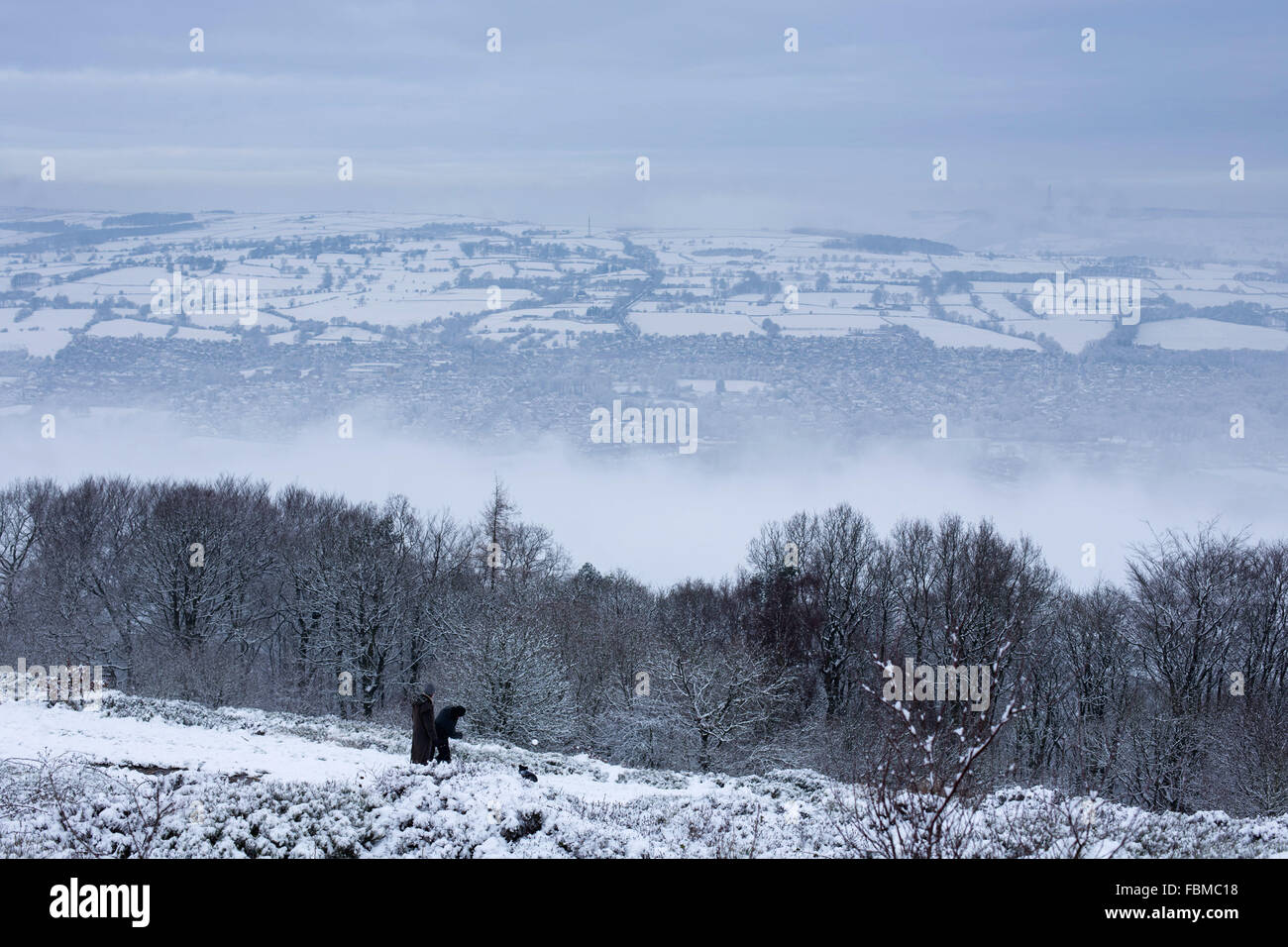 Ein Mann wirft einen Schneeball für seinen Hund während Schneeverhältnissen in Otley Chevin in Otley, West Yorkshire. Stockfoto