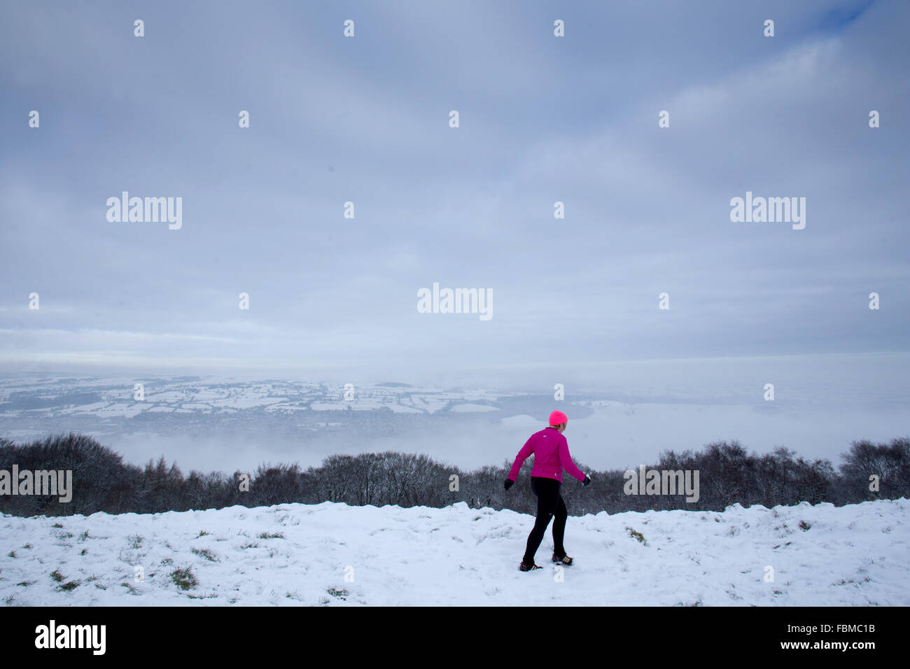 Ein Jogger läuft während der schneereichen Bedingungen auf dem Gipfel des Otley Chevin, West Yorkshire. Stockfoto