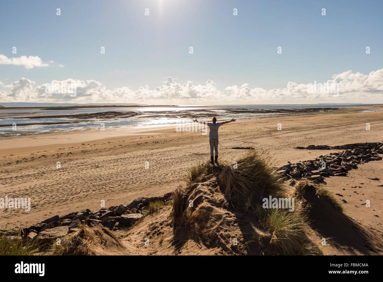 Mann mit ausgestreckten Armen stehend auf Sand Düne am Strand Stockfoto