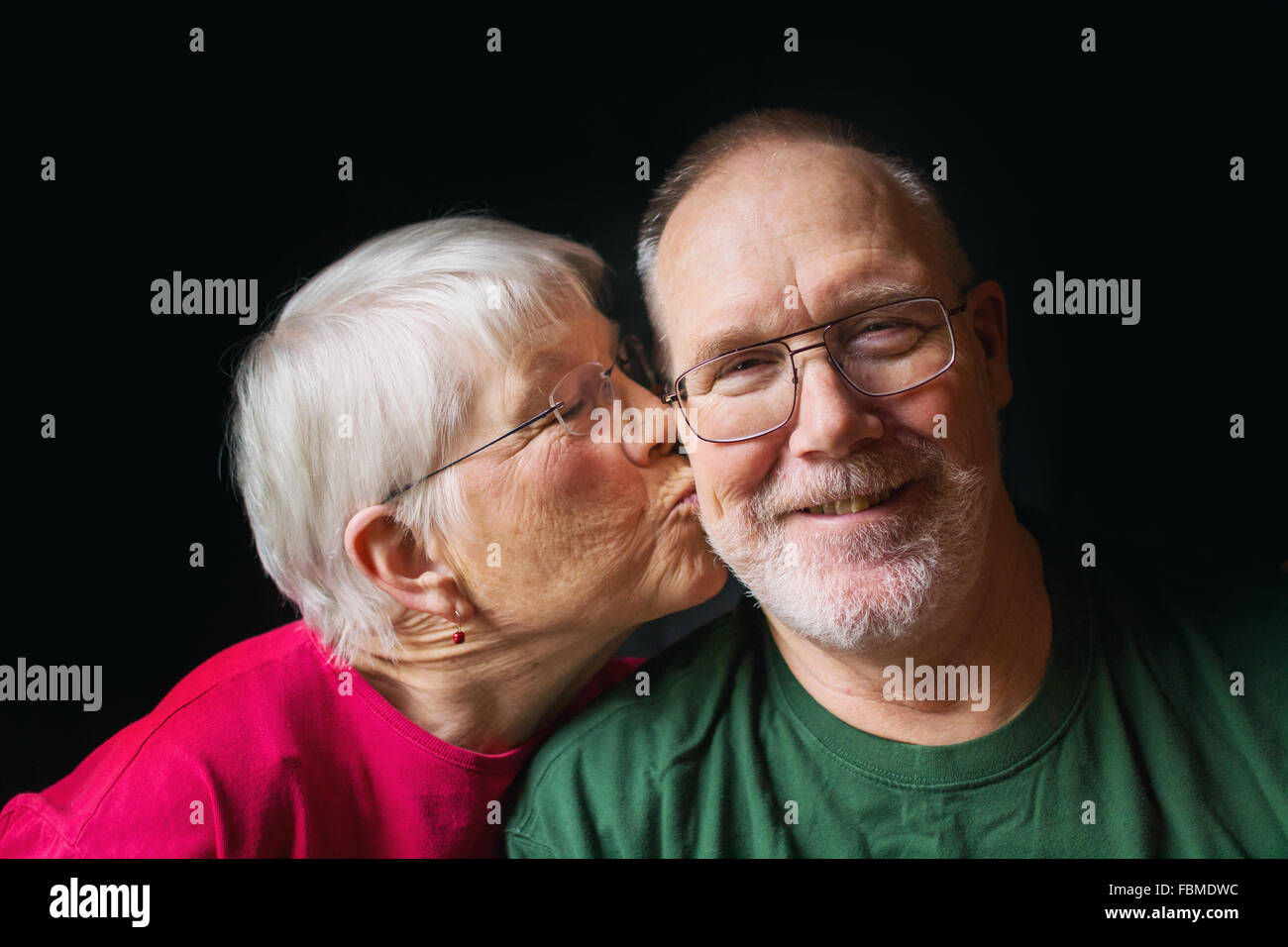 Ältere Frau küssen Wange des älteren Menschen Stockfoto