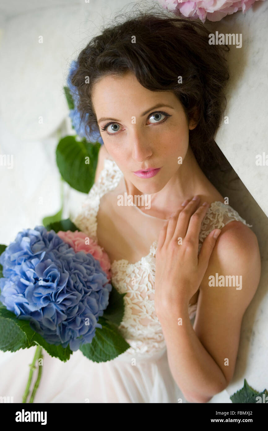 Frauen auf Marmorstufen liegend mit Hortensie im Hochzeitskleid Stockfoto