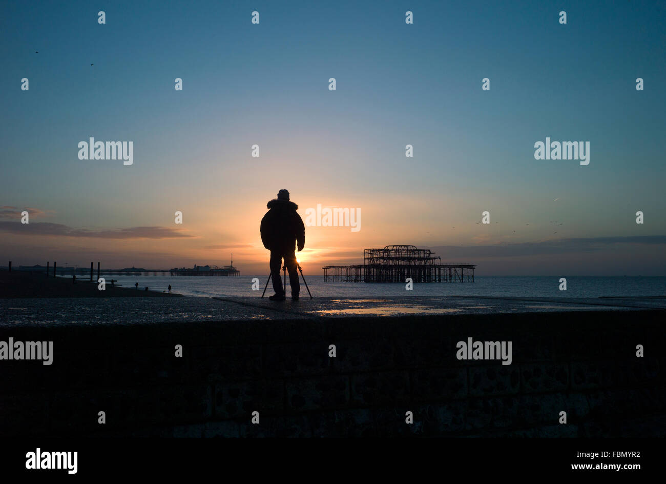 Fotograf mit Stativ Silhouette gegen aufgehende Sonne, Brighton, UK Stockfoto