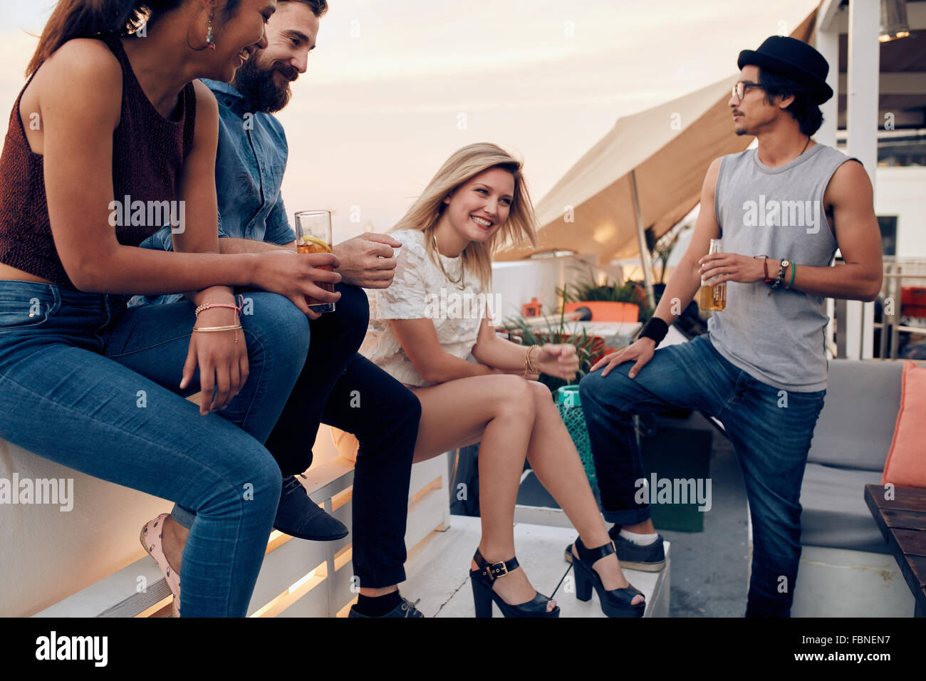 Gruppe von Freunden auf einem Dach, die Getränke hängen. Jugendliche feiern zusammen mit Cocktails. Stockfoto