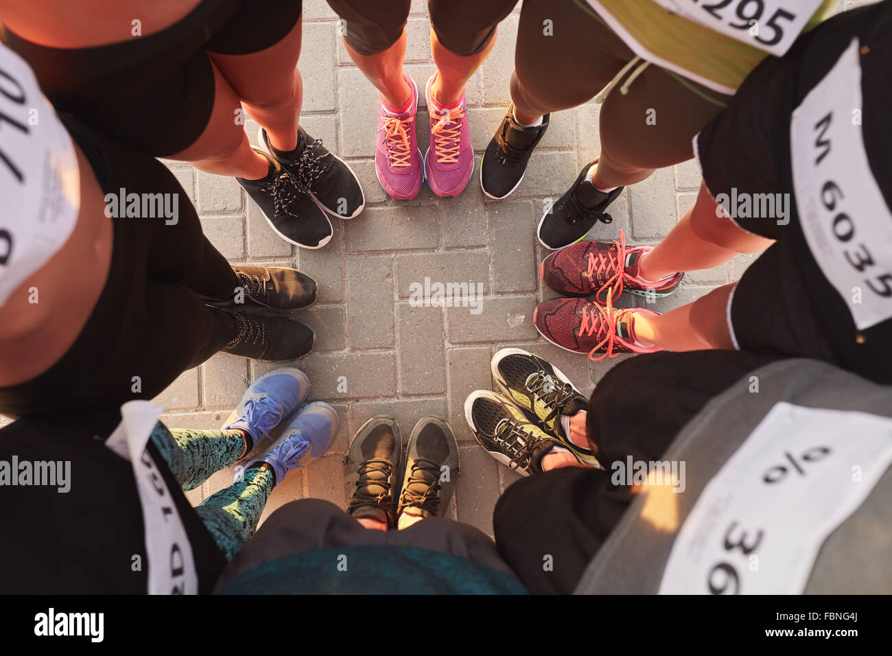 Draufsicht der Füße von Menschen stehen in einem Kreis. Läufer, die zusammen in ein Wirrwarr mit den Füßen stehen. Stockfoto